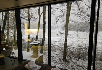 Uitzicht vanuit de ÖÖD Suite tiny house bij Wilsumer Berge in Duitsland met sneeuw en bomen.