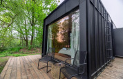 Nokken Forest Cabin en Wilsumer Berge, Alemania, pequeña casa moderna negra con terraza y vistas al bosque.
