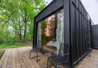 Nokken Forest Cabin en Wilsumer Berge, Alemania, pequeña casa moderna negra con terraza y vistas al bosque.