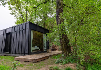 Sort Nokken Forest Cabin ved Wilsumer Berge i Tyskland omgivet af frodig grøn skov og træer.