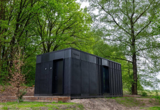 Tiny house Nokken Forest Cabin negra en plena naturaleza verde en Wilsumer Berge, Alemania.