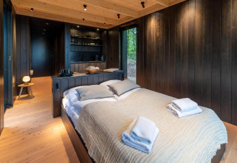 Moderne soveværelse med træinteriør i Nokken Forest Cabin, Wilsumer Berge, Tyskland, med dobbeltseng.