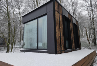 Moderne Nokken NKN-18 tiny house på Wilsumer Berge i Tyskland med sneklædt terrasse og skovbaggrund.