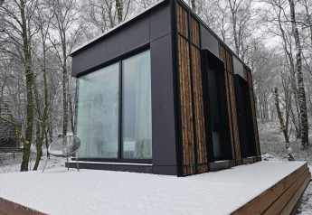 Tiny house Nokken NKN-18 a Wilsumer Berge, Germania, con terrazza innevata e foresta sullo sfondo.