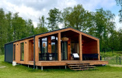 Casa moderna de madera con fachada de cristal, The Beach House en Wilsumer Berge, Alemania, rodeada de árboles.