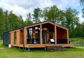 Casa moderna de madera con fachada de cristal, The Beach House en Wilsumer Berge, Alemania, rodeada de árboles.