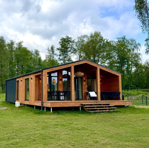 Modern houten lodge met glazen gevel, The Beach House bij Wilsumer Berge in Duitsland, omringd door bomen.
