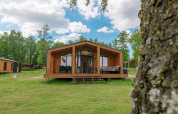 Moderne træhytte ved The Beach House, Wilsumer Berge, Tyskland, omgivet af grøn natur og blå himmel.