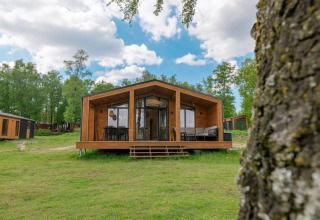 Moderne houten lodge bij The Beach House, Wilsumer Berge, Duitsland, omringd door groen en blauwe lucht.