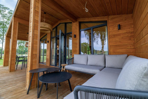Udendørs terrasse med træpaneler, moderne sofaer og borde på The Beach House ved Wilsumer Berge i Tyskland.