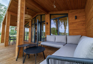 Terrazza in legno moderna con divani e tavolini al The Beach House presso Wilsumer Berge in Germania.