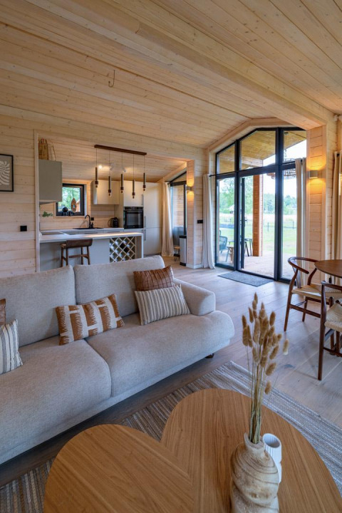 Sala luminosa y moderna en The Beach House, Wilsumer Berge, Alemania, con decoración de madera y grandes ventanas.