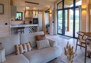 Sala luminosa y moderna en The Beach House, Wilsumer Berge, Alemania, con decoración de madera y grandes ventanas.