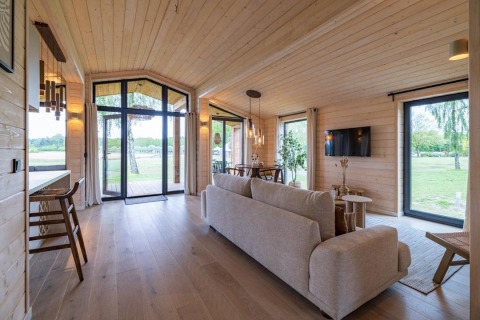 Lichte, moderne woonkamer in The Beach House bij Wilsumer Berge, Duitsland, met grote ramen en uitzicht.