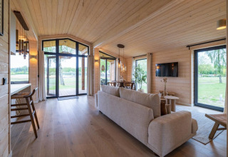 Lichte, moderne woonkamer in The Beach House bij Wilsumer Berge, Duitsland, met grote ramen en uitzicht.
