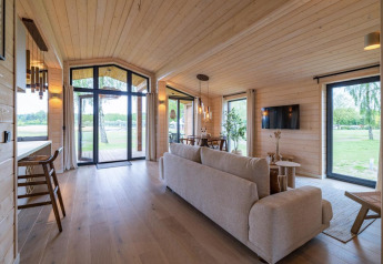 Salon moderne et lumineux au Beach House à Wilsumer Berge en Allemagne, avec grandes fenêtres et vue sur la nature.