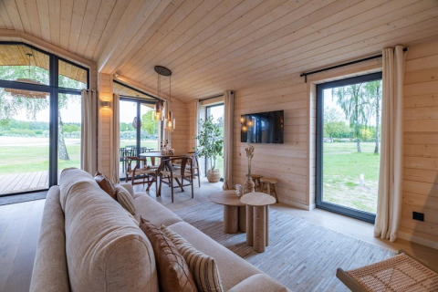 Lichte, moderne woonkamer in The Beach House bij Wilsumer Berge, Duitsland, met grote ramen en uitzicht.