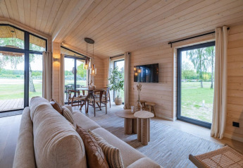 Luminoso salón moderno en The Beach House en Wilsumer Berge, Alemania, con grandes ventanas y vistas al exterior.