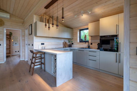 Cocina moderna en The Beach House en Wilsumer Berge, Alemania, con paneles de madera clara y barra de desayuno.