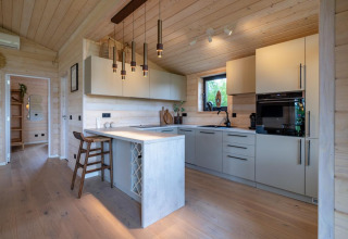 Cocina moderna en The Beach House en Wilsumer Berge, Alemania, con paneles de madera clara y barra de desayuno.