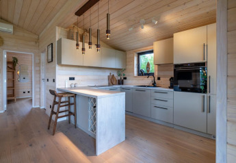 Cocina moderna en The Beach House en Wilsumer Berge, Alemania, con paneles de madera clara y barra de desayuno.