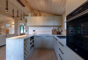 Cocina moderna en The Beach House en Wilsumer Berge, Alemania, con madera clara y luces colgantes elegantes.