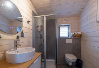 Baño moderno con paneles de madera, ducha, lavabo y váter suspendido en The Beach House, Wilsumer Berge.