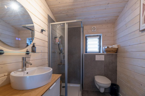 Moderne badeværelse med træpaneler, bruser, håndvask og væghængt toilet i The Beach House, Wilsumer Berge.