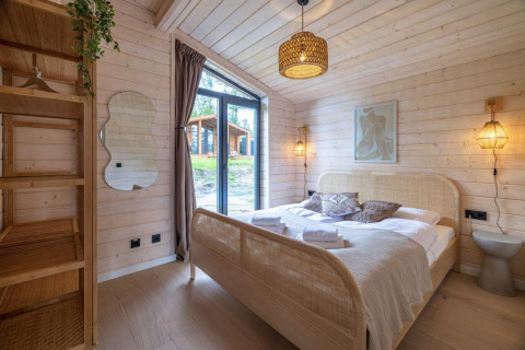 Hyggeligt soveværelse med trævægge, stor seng og vindue i The Beach House ved Wilsumer Berge, Tyskland.