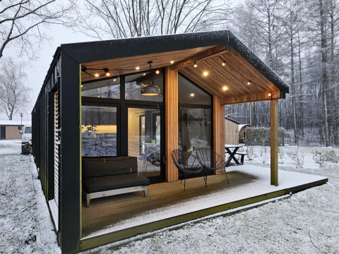 Cabaña moderna con grandes ventanales y terraza cubierta en un paisaje nevado en Wilsumer Berge, Alemania.