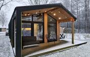 Cabaña moderna con grandes ventanales y terraza cubierta en un paisaje nevado en Wilsumer Berge, Alemania.