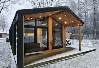 Cabaña moderna con grandes ventanales y terraza cubierta en un paisaje nevado en Wilsumer Berge, Alemania.