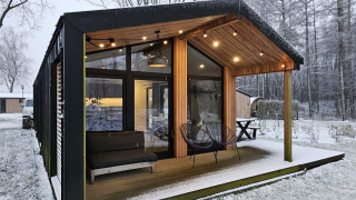 Moderne hytte med store vinduer og overdækket terrasse i snedækket landskab ved Wilsumer Berge, Tyskland.