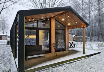 Modern lodge with large windows and covered terrace in a snowy landscape at Wilsumer Berge, Germany.