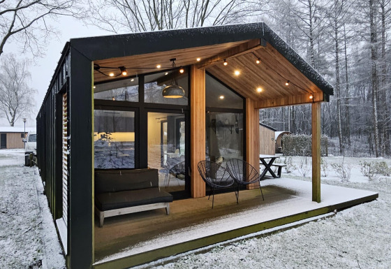 Moderne lodge met grote ramen en overdekt terras in een besneeuwd landschap bij Wilsumer Berge, Duitsland.