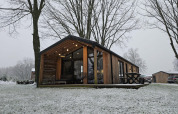 Cabane moderne en bois à Nature Lodge, Wilsumer Berge, Allemagne, entourée de neige et d’arbres en hiver.