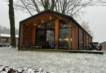 Moderno lodge in legno al Wilsumer Berge, Germania, circondato da neve e alberi spogli invernali.