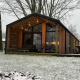 Lodge moderne en bois à Wilsumer Berge, Allemagne, entourée de neige et d'arbres dénudés en hiver.
