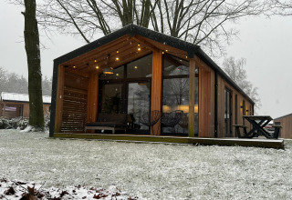 Cabaña moderna de madera en Wilsumer Berge, Alemania, rodeada de nieve y árboles de invierno desnudos.