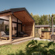 Cabaña de madera moderna con terraza cubierta, asientos al aire libre y bañera exterior en plena naturaleza.