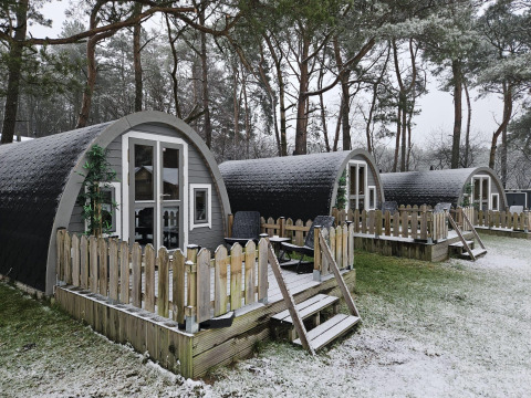 Kleine Holzhütten mit Veranda und leichtem Schnee im Wald bei Woodlodge, Wilsumer Berge, Deutschland.