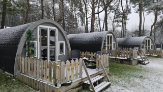 Pequeñas cabañas de madera con terrazas nevadas en el bosque de Woodlodge, Wilsumer Berge, Alemania.