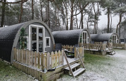 Pequeñas cabañas de madera con terrazas nevadas en el bosque de Woodlodge, Wilsumer Berge, Alemania.