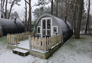 Cabaña de madera nevada con terraza en un bosque, tomada en Woodlodge en Wilsumer Berge, Alemania en invierno.