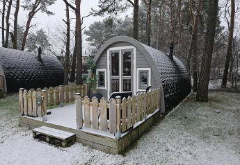 Chalet en bois enneigé avec terrasse, situé en forêt à Woodlodge, Wilsumer Berge, Allemagne en hiver.