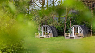 Twee charmante, ronde lodges bij Woodlodge Wilsumer Berge in Duitsland omgeven door groen gebladerte.