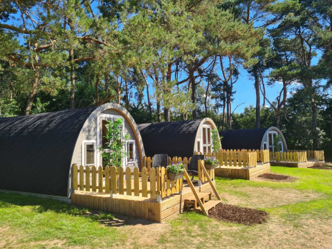 Træhytter med små terrasser ved Woodlodge i Wilsumer Berge, Tyskland, omgivet af grønne træer.