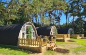 Knusse houten huisjes met terrassen bij Woodlodge in Wilsumer Berge, Duitsland, tussen de bomen.