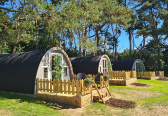 Træhytter med små terrasser ved Woodlodge i Wilsumer Berge, Tyskland, omgivet af grønne træer.