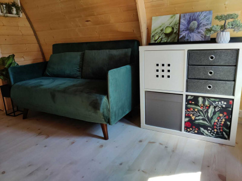 Billede af en grøn sofa og en moderne hvid reol i en træhytte ved Woodlodge, Wilsumer Berge, Tyskland.